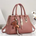 Nahaufnahme einer eleganten rosa Lederhandtasche mit Goldbeschlägen und Pferdeanhänger. - 28/14/20 / Rosa