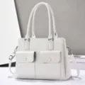 White PU leather tote bag detail showcasing dual front flap pockets and sturdy top handles. - White