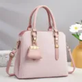 Gros plan sur les détails du sac à main monogrammé rose avec quincaillerie dorée et charm. - Rose