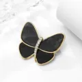 Closeup detail of a chic butterfly brooch with black resin wings and crystal gold body. - Style 1 / Black