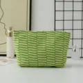 Detailed view of a stylish green and white knitted makeup bag, featuring textured stripe design. - Beige and Green Stripes
