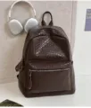 Nahaufnahme eines dunkelbraunen geflochtenen PU-Leder-Rucksacks, stilvolles Alltags-Accessoire. - Braun