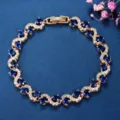Elegant gold-plated cross bracelet featuring sparkling blue and white cubic zirconia stones. - Gold and Blue