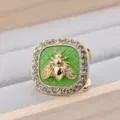 Dettaglio ravvicinato di una fibbia per sciarpa quadrata con bordo in strass e ape dorata. - Verde