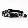 Close up detail of black pet collar featuring white paw print pattern and safety bell. - Paw Print Style / Black