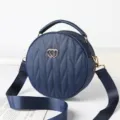 Stylish blue circular quilted crossbody bag with top handle and wide strap for women. - Blue
