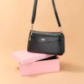 Women's black PU leather crossbody bag with chic metallic bow decoration and long strap. - Black