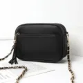 Trendy black leather women crossbody bag with gold chain strap and stylish tassel charm. - Black