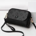Stylish black leather crossbody bag with embossed monogram pattern and gold hardware for women. - Black
