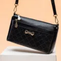 Retro black textured leather shoulder crossbody bag with golden bow hardware for women commuting. - Black