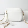 White PU leather crossbody shoulder bag with gold chain strap and stylish tassel charm detail. - White
