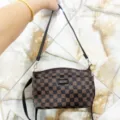 Detailed view of brown checkerboard shoulder bag with black strap and metallic hardware accents. - Lattice Floral
