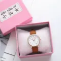 Detailed view of the cute pink quartz watch with brown leather strap and rose gold case. - Coffee