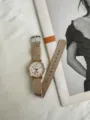Detailansicht einer minimalistischen Canvas-Armbanduhr mit rundem Roségoldgehäuse und Zifferblatt. - Weißes Armband