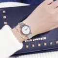 Close up of minimalist silver quartz watch with mesh strap and cute leaf bracelets on bag. - Unique Silver Band Marker White Dial