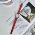 Detailaufnahme einer schicken roten Lederarmband-Quarzuhr mit einem kleinen weißen Zifferblatt. - Rotes Band