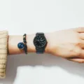 Detailansicht der schwarzen Sternzeichen Quarzuhr mit Perlenarmband am Handgelenk stilsicher - Krebs