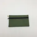 Nahaufnahme des einfachen grünen Canvas-Reißverschlussetuis mit Textur und Metallring. - Armeegrün
