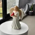 Detail view of the resin angel figurine holding a red cardinal bird for home desk decor. - Angel and Bird Ornament