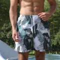 Close-up detail of men's tropical leaf printed board shorts with white drawstring. - Green Leaf