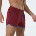 Primo piano dei dettagli di pantaloncini sportivi in rete traspirante con bordatura blu. - viola-rosso