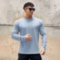 Detailansicht des strukturierten Herren-Pullovers, zeigt Stoff und Passform an der Wand. - Hellblau