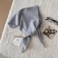 Primo piano di una sciarpa triangolare in lana grigia accogliente su texture morbida invernale. - Grigio chiaro