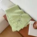 Green knit scarf for women, featuring cute black bow embroidery for cozy autumn winter style. - Green