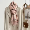 Detailopname van een gezellige roze geruite winterscarf over een stijlvolle jas gedrapeerd. - 200cm / Roze
