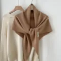 Gedetailleerd overzicht van de elegante bruine wollen driehoekssjaal aan de hanger. - camel