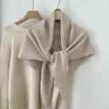 Detailopname van gezellige gebreide wollen driehoekssjaal in haverkleur, elegante drapering. - Beige