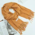 Detailopname van mosterdgele kasjmierachtige ruitjes wintershawl met elegante franjes. - camel