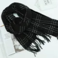 Black plaid winter scarf with white grid pattern and tassel fringe, cozy and warm apparel. - Black