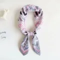 Detailed close-up view of the pink and grey geometric printed silk scarf, showing knots. - Striped Pink
