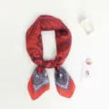 Detailed shot of a stylish paisley print silk scarf with vibrant red and purple tones. - Red Leaf