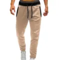 Close-up detail of casual khaki sweatpants with black waistband, drawstrings and zipper pockets. - Khaki