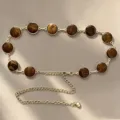 Nahaufnahme der goldenen Damen-Tailleette mit braunen Marmormotiven, modisches Accessoire. - Tigerauge Taillenkette