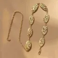 Goldene Taillenkette aus Metall mit verzierten ovalen Durchbruchplättchen. Elegantes Accessoire. - Unregelmäßige Spleiß-Taillenkette / Gold
