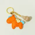 Orange leather horse keychain featuring crystal gourd pendant, stylish bag charm accessory. - Topaz