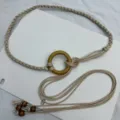 Close-up detail of bohemian beige braided rope belt with wooden ring and bead tassel decor. - Khaki