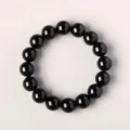 Close up shot of black obsidian bead bracelet showing glossy round smooth surface details. - Standard Single Eye Obsidian / 10mm