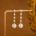 Elegante lange Ohrringe mit funkelnden Zirkonia-Tropfen und glänzenden weißen Perlen in Gold. - Gestufter Birnenförmiger Zirkonia Stil (e2342 Gold)