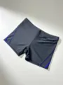 Men's black swim trunks detail view, featuring blue side piping for stylish athletic look. - M / Black