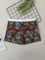 Detailed view of men's board shorts with colorful floral skull print and white waistband. - Skull