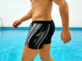 Detail view of men's athletic swim trunks featuring contrast stripes and drawstring. - Gray