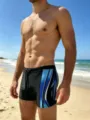 Detailed shot of men's athletic swim trunks with blue stream prints and drawstring waist. - Blue