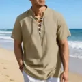 Detail shot of a men's beige short sleeve lace-up shirt worn on a sunny beach background. - S / Tops / Khaki