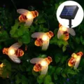 Vista detallada de adorables luces LED de abejas que brillan cálidamente entre hojas. - 5 Metros 20 LEDs Solar / Blanco cálido