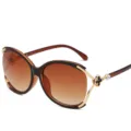 Gafas de sol grandes para mujer con lentes degradadas, montura dorata y detalle de trébol. - Montura Marrón Degradado Marrón