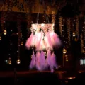 Primo piano di un acchiappasogni rosa luminoso in piuma con pizzo e luci LED al buio. - Senza luci / Rosa